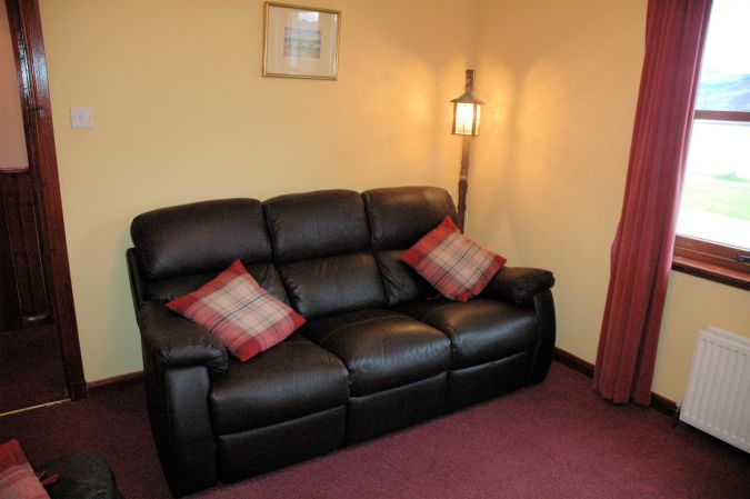 The lounge/sitting room in Tarlogie is comfortably furnished with 2 leather settees.